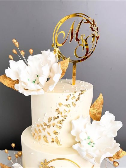 The top tier of our engagement cake, featuring a personalized gold acrylic topper with the couple's initials. This is a wonderful way to add a personal element that can be kept as a memento.
