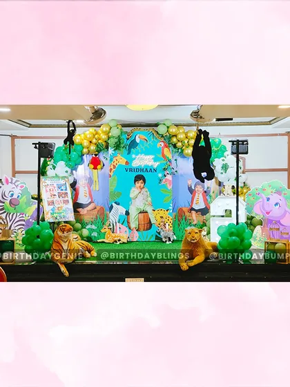 I designed this expansive jungle safari stage to create a wild adventure for a second birthday. The setup includes a personalized backdrop, numerous life-sized animal cutouts like a tiger, elephant, and giraffe, and lush green and gold balloon arrangements to complete the jungle vibe.