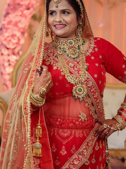 A full-length view of the bride, showcasing how the grand jewellery set complements her red bridal lehenga. This entire look can be achieved through my rental service.