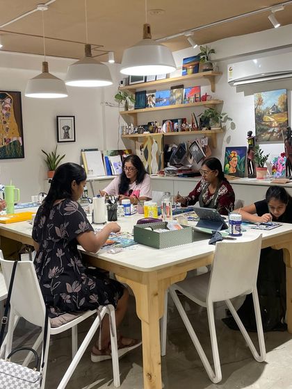 A snapshot of a full class, with participants of all ages engaged in a painting and drawing session.