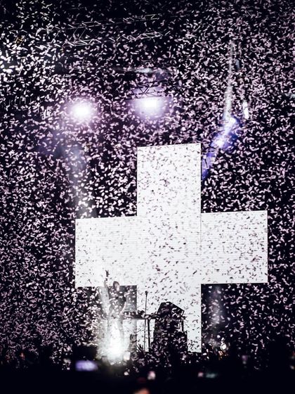 A shower of confetti against the stark white cross of the Martin Garrix stage design.