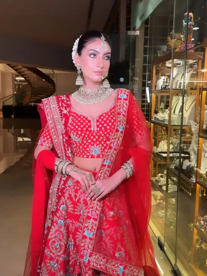 This shot captures the bride in a beautiful setting, her red outfit standing out. The makeup is flawless, ensuring she is picture-perfect from every angle.