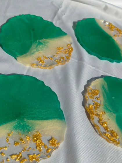 A set of four geode-style resin coasters in a vibrant emerald green and white design, finished with a touch of gold flake for a luxurious look.