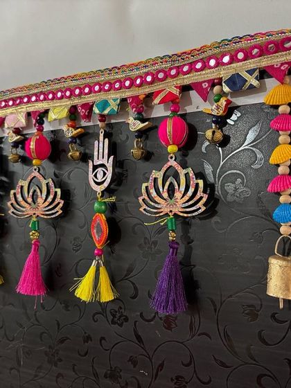 The full view of the 'Shubh Toran' against a dark background, making its bright colors and intricate details stand out.
