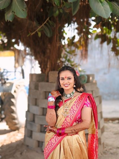 A full portrait of the bride in her Radha inspired look, standing under a tree.