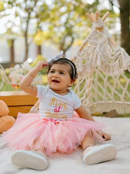 An outdoor first birthday picnic is a wonderful way to celebrate. This little girl, in her adorable tutu, is all smiles surrounded by her favorite teddy bears and a cute teepee tent.