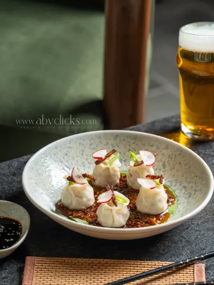 A bowl of chili oil wontons paired with a glass of beer at Camo, Noida.
