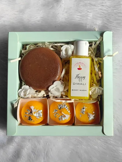 A clean, top-down view of the Diwali gift set, showing the chocolate-scented soap, three ladoo candles, and festive body wash.
