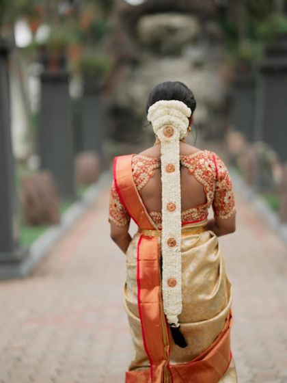 The back view is just as important as the front. Here, you can see the traditional South Indian bridal braid, beautifully decorated with jasmine flowers, perfectly complementing her silk saree.