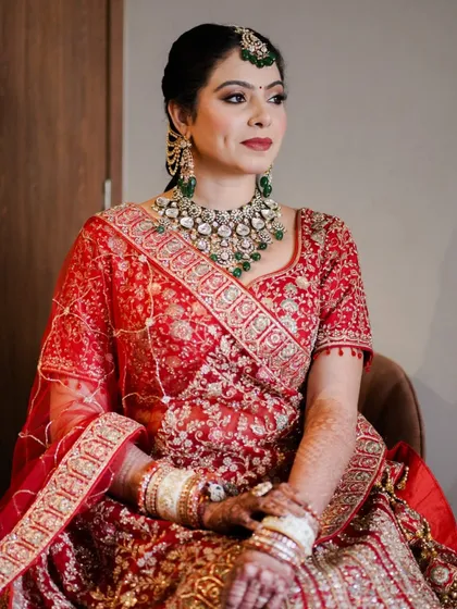 A seated portrait that captures the richness of her lehenga and the elegance of her makeup. The deep red lip and softly defined eyes are a classic combination that never fails.