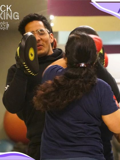 An instructor holding pads for a member during a kickboxing session. This shows the hands-on, personalized training you receive in our group classes to ensure you're learning and improving.