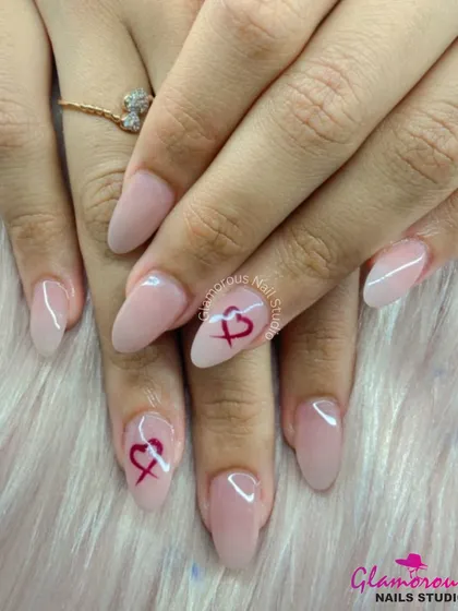 A minimalist and romantic design, this set features sheer nude almond-shaped nails with a small, hand-painted heart on two accent fingers.