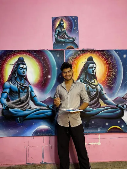 A photo of me with my brushes and palette next to the completed cosmic Shiva commissions.