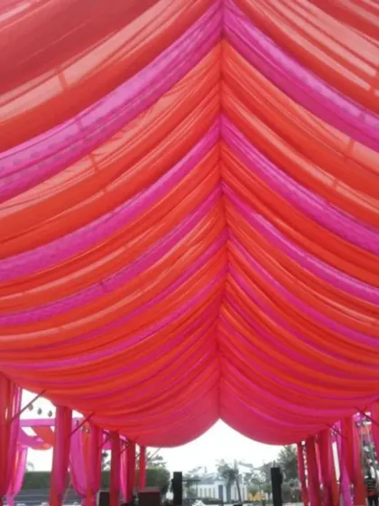 This vibrant outdoor setup uses bright pink and orange drapes to create a colorful canopy. This is a simple yet effective way we create a festive atmosphere for daytime functions like Mehendi or Haldi.