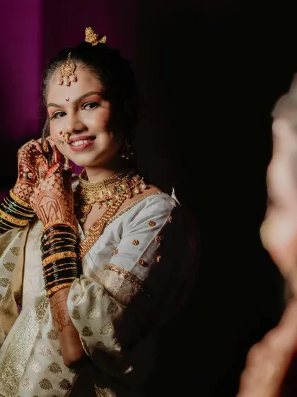 The bride adjusts her earring while looking in the mirror. This candid getting-ready shot is a beautiful way to capture the final moments of anticipation before she walks down the aisle.