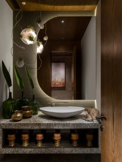 Even the most functional spaces are an opportunity for artistry. This powder room is designed as a jewel box, where a sculptural stone vanity, artisanal brassware, and dramatic Bocci lighting transform a simple utility area into a corner of unexpected beauty and detail.