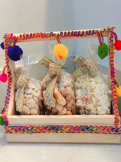 A simple yet festive Lohri hamper in a wooden tray, containing three bags of traditional treats.