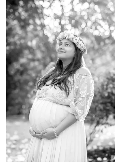 A hopeful and radiant solo portrait in black and white. The monochrome tones highlight the soft light and the mother's glowing expression as she looks upward.