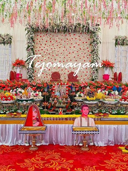 A beautiful engagement setup with a backdrop of hanging flowers and personalized caricature props for the bride and groom.