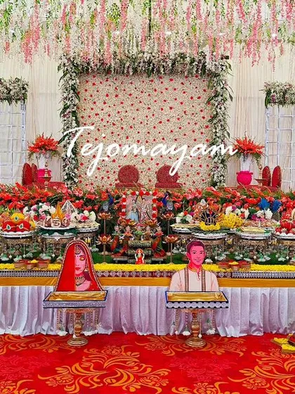 A grand engagement setup with a backdrop of hanging flowers and a long, colorful plate decoration.
