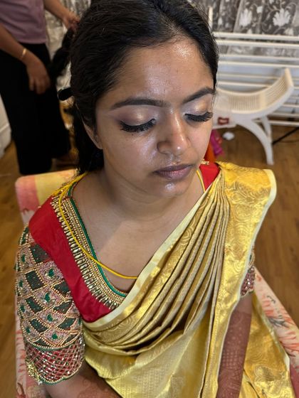 A behind-the-scenes moment during the draping process. You can see the beginnings of the look, with the eye makeup done and the saree being set perfectly.