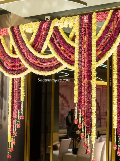 A close-up of the intricate floral drapery over the doorway. The dense garlands of red and yellow flowers create a rich and celebratory welcome for guests.