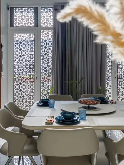 We believe dining areas should be inviting. In this space, we used intricate jali work on the windows to filter light beautifully, creating a serene ambiance around the contemporary dining set.