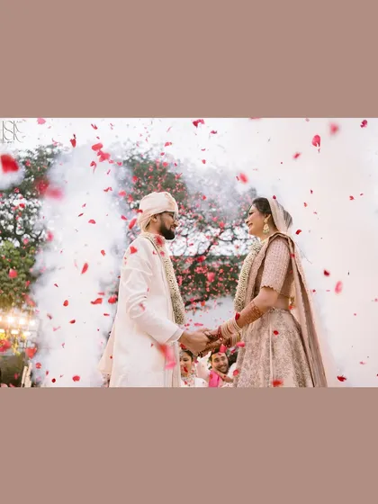 A magical moment as the couple holds hands, surrounded by rose petals and smoke. This shot feels like a scene from a fairytale.