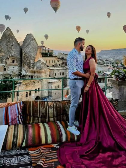 A romantic shot of a couple on a rooftop in Cappadocia, with the bride wearing my deep magenta trail gown.