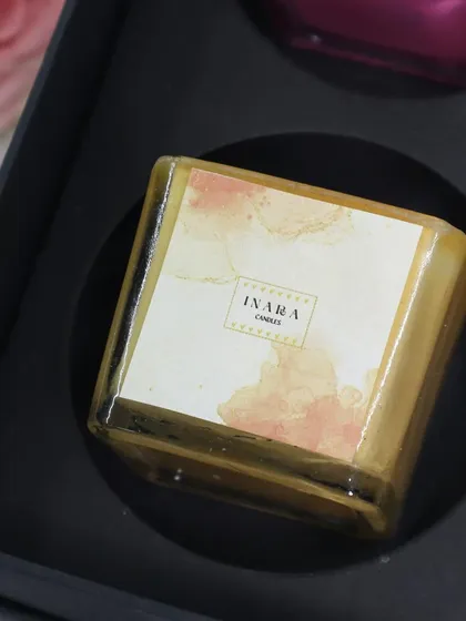 A close-up of the beautiful yellow candle from our square glass jar gift set. Each candle features a unique, watercolor-style label for a touch of artistry.