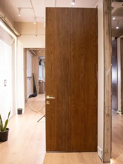 A full view of the minimalist fluted door, showing how it integrates seamlessly into a modern, open-plan space. The simplicity of the design is its greatest strength.