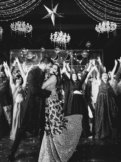 A perfect black and white shot of the couple's finale, surrounded by their cheering friends and family. A timeless memory of a perfect sangeet.