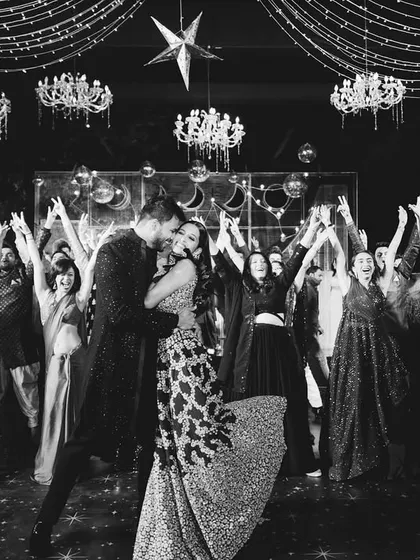 A perfect black and white shot of the couple's finale, surrounded by their cheering friends and family. A timeless memory of a perfect sangeet.