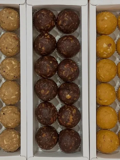 A trio of our best-selling homemade desi ghee laddoos. This image displays our classic Atta Panjiri, rich Date and Walnut (a sugar-free option), and traditional Besan laddoos, showing the variety available for your festive boxes.