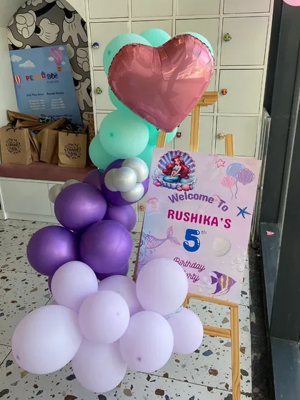 An "Under the Sea" adventure begins here. This welcome sign for Rushika's 5th birthday features Ariel, pastel balloons, and a heart-shaped foil balloon.