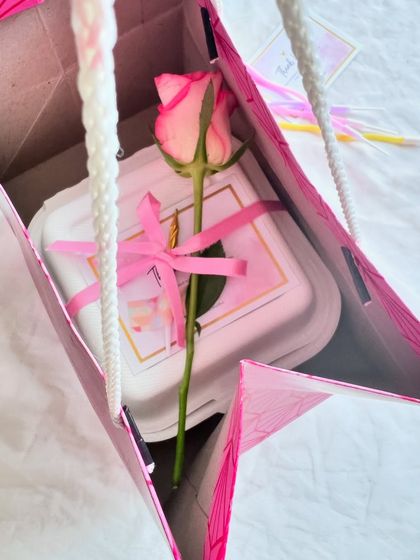 The complete gift set. A beautifully wrapped bento cake with a fresh flower, placed in a stylish gift bag, ready to make someone's day.