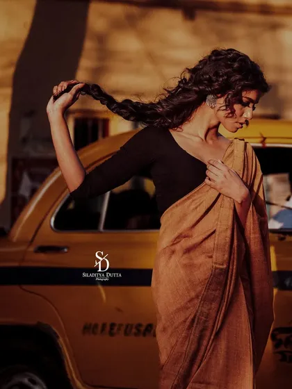 A model posing with a classic yellow ambassador taxi. This shot is quintessentially Kolkata, blending fashion with the city's iconic imagery and warm, golden-hour light.