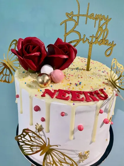 A beautiful combination of trends, this cake features a white chocolate drip, deep red roses, and golden butterflies. It's an elegant and eye-catching design perfect for a birthday or anniversary.