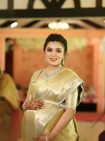 A full-length portrait of Monica at her baby shower. Her makeup is polished and elegant, completing her stunning look and celebrating her radiant pregnancy glow.