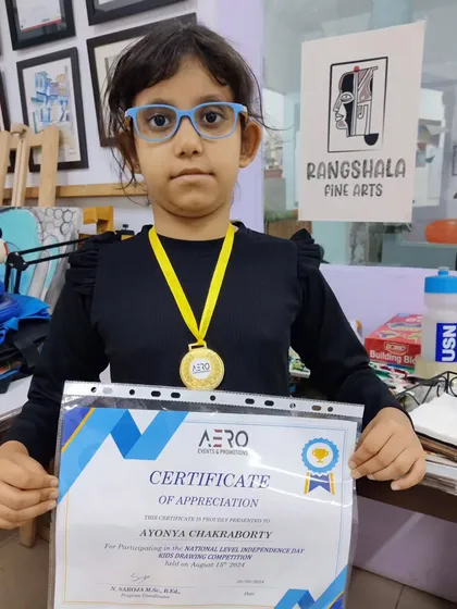 We celebrate our students' successes. Here, one of our young artists proudly displays her gold medal and certificate from a national-level drawing competition, a testament to the quality of our training.