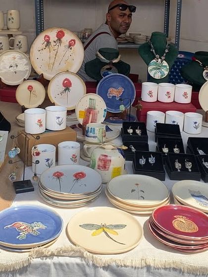 A beautiful display of hand-painted ceramics, featuring plates, mugs, and bowls with delicate floral and dragonfly motifs.