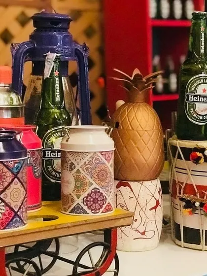 This setup combines rustic and traditional elements. A miniature cart, patterned canisters, and a dhol create a quirky and colorful corner at a Funjabi-themed event, perfect for serving beer or signature cocktails.