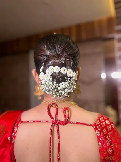 A closer look at the modern floral bun, featuring a clean, sleek finish with a crown of baby's breath. This style is perfect for securing a dupatta.