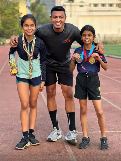 A coach's proud moment with two of our young champions, showcasing their medals and trophies. Their hard work and dedication are truly inspiring.