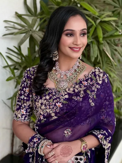 A candid side profile, capturing the shimmer of the saree and the client's happy expression.