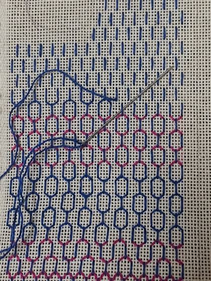 A phone insert being embroidered. You can see the needle and thread at work, slowly building the intricate pattern.