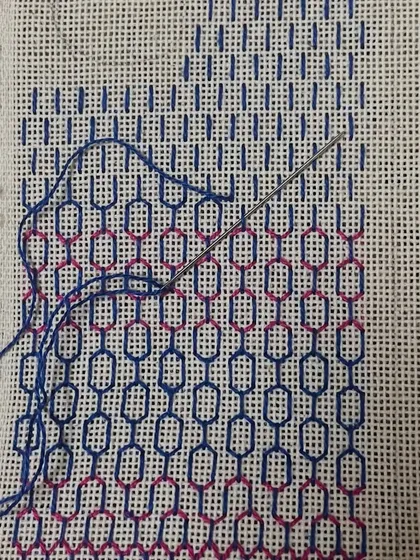 A phone insert being embroidered. You can see the needle and thread at work, slowly building the intricate pattern.