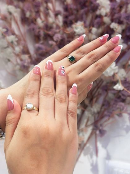 The epitome of elegance, this French manicure on almond-shaped nails is enhanced with tiny, delicate floral details and rhinestones. It's a soft, feminine, and timeless look.