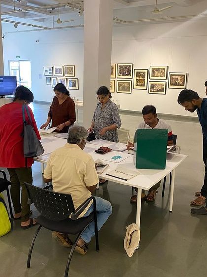 Visitors at the 'Hand Prints' exhibition engaging with the library table, which offered books and journals for deeper reading.