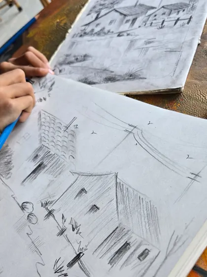 Our classes are a place for artists of all ages to grow. This photo shows one of our young students diligently practicing their landscape sketching, receiving hands-on guidance to build their foundational drawing skills.